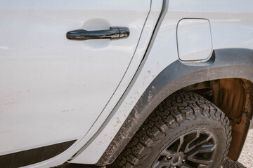 A white SUV truck car with mud on the wheel after driving through the wilderness of Flinders Ranges during a road trip in the outback of Australia.