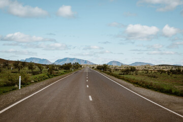 A beautiful mountain landscape with an empty asphalt road outdoor at daytime during springtime season during a road trip in Flinders Ranges in the outback of Australia with space for text.