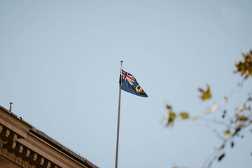 The beautiful multi coloured South Australian flag fluttering in the wind framed by some leaves outdoor at daytime during winter in Austrlia with space for text.