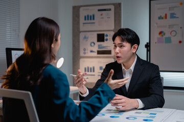 Asian colleagues discussing business data in office meeting