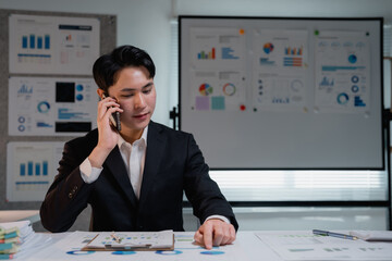 Asian businessman calling on smartphone analyzing financial data