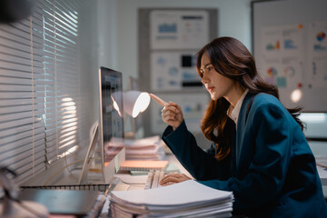 Businesswoman working late on computer analyzing data at office