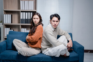 Asian couple having relationship problems on sofa after arguing