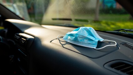 surgical mask on dashboard with sunlit vent area and crisp shadows creating calm post pandemic