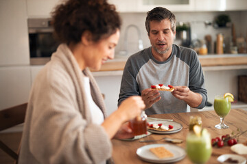 Couple Sharing Brunch At Home With Toast, Strawberries, And Green Smoothies In Kitchen