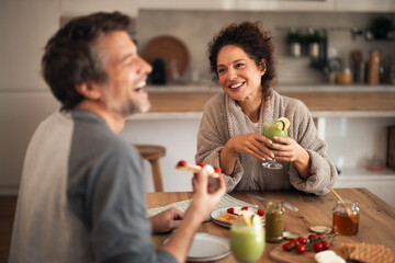 Happy Couple Enjoying Morning At Home Breakfast With Green Smoothies And Toast