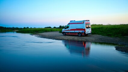 ambulance near riverbank approaching camera on empty rural road with calm setting