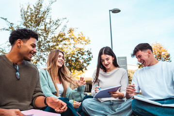 Diverse university students laughing, studying together outdoors