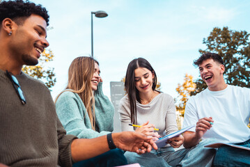 Diverse students group studying together and laughing outdoors