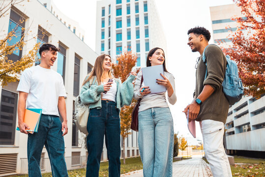 Diverse students laughing talking walking on campus outdoors