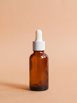 Different serum cosmetic bottles, white and dark brown dropper bottle container and packaging skincare product. studio pastel light background.
