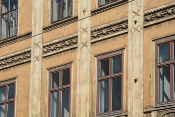 Close up of an old yellow building facade in Zagreb featuring classic architectural details decorative stone ornaments and brown window frames