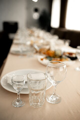 Elegant table setting for a banquet or wedding reception in a restaurant. Selective focus on crystal glasses and white plates