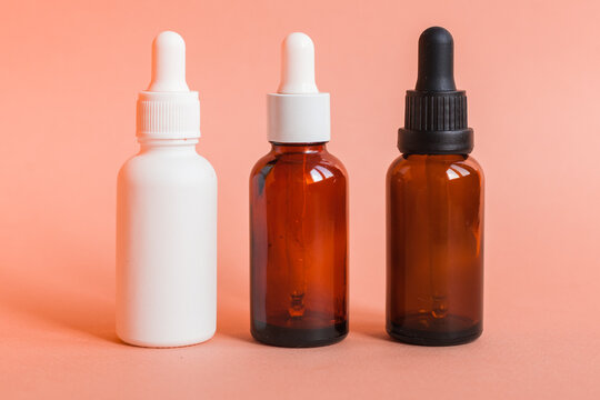 Different serum cosmetic bottles, white and dark brown dropper bottle container and packaging skincare product. studio pastel light background.