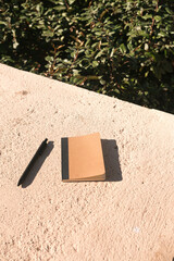 Notebook mockup with black pen on rock surface at the park. Creative flat lay concept for template mockup.