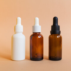 Different serum cosmetic bottles, white and dark brown dropper bottle container and packaging skincare product. studio pastel light background.