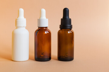 Different serum cosmetic bottles, white and dark brown dropper bottle container and packaging skincare product. studio pastel light background.