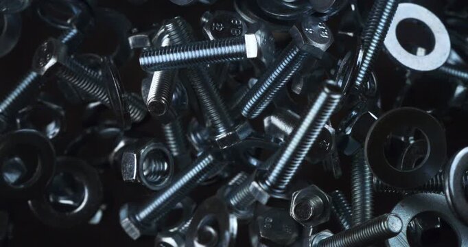 Ultra slow motion close-up of stainless steel nuts and bolts flying, spinning, and colliding in midair at 1000 fps, reflecting light and showcasing precise mechanical energy.