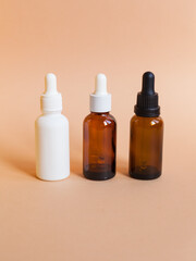 Different serum cosmetic bottles, white and dark brown dropper bottle container and packaging skincare product. studio pastel light background.
