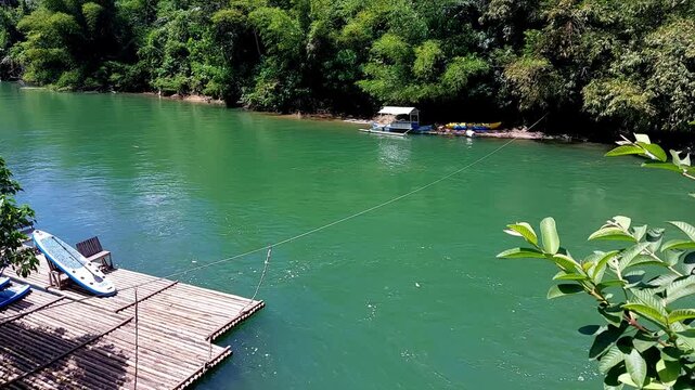 Bamboo raft and a paddle board on the calm water of Loboc River with lush forest creating an enchanting summer scenery. Bohol, Philippines
