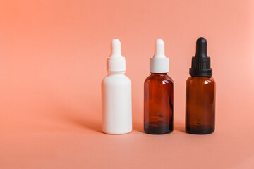 Different serum cosmetic bottles, white and dark brown dropper bottle container and packaging skincare product. studio pastel light background.
