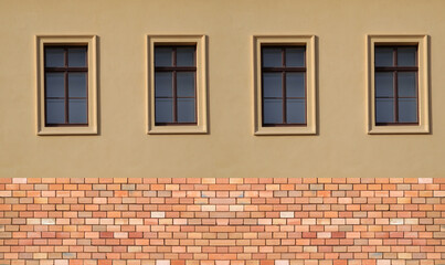 Hausfassade mit vier Fenstern und Klinkersockel