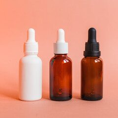 Different serum cosmetic bottles, white and dark brown dropper bottle container and packaging skincare product. studio pastel light background.