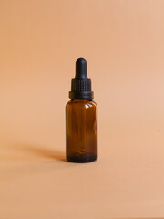 Different serum cosmetic bottles, white and dark brown dropper bottle container and packaging skincare product. studio pastel light background.