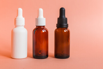 Fototapeta premium Different serum cosmetic bottles, white and dark brown dropper bottle container and packaging skincare product. studio pastel light background.