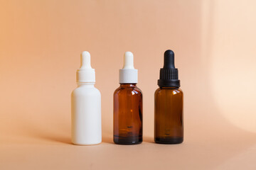 Different serum cosmetic bottles, white and dark brown dropper bottle container and packaging skincare product. studio pastel light background.