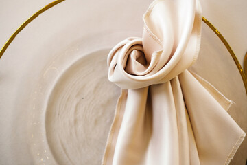 Elegant folded fabric napkin in a circular glass bowl with a gold rim, showcasing sophisticated table setting and modern dining aesthetics for upscale events