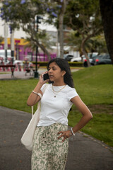 A young girl is talking on her cell phone while walking down a sidewalk