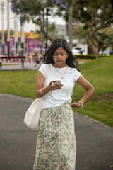 A young girl is walking down a sidewalk while looking at her cell phone