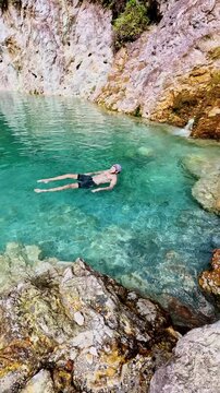 A tranquil scene of a swimmer floating in clear blue water of JABA sulfur lagoon in Tanjay, Negros Oriental, Philippines