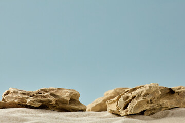 Empty stone podium on sand with blue background for product placement.