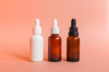 Different serum cosmetic bottles, white and dark brown dropper bottle container and packaging skincare product. studio pastel light background.