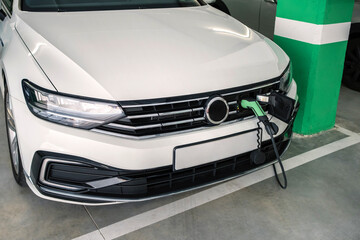 Modern white electric car charging at station in parking garage, highlighting sustainable transportation and clean energy solutions for the future of automotive technology