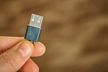 Close-up of a hand holding a USB Type-A cable.