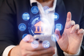 Business person uses phone with digital finance icons displayed, showing a modern approach to banking and financial services in a professional setting