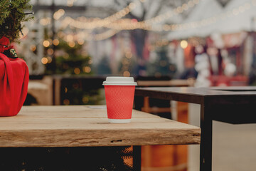 Red Takeaway Coffee Cup on Wooden Table in Cozy Outdoor Cafe