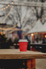 Red Takeaway Coffee Cup on Wooden Table in Cozy Outdoor Cafe
