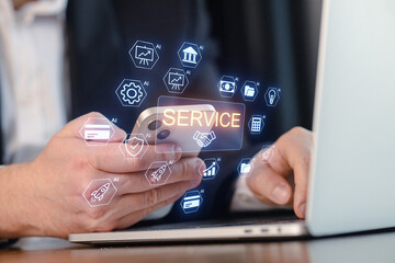 Man using smartphone and laptop with icons related to service and technology in digital workspace setting