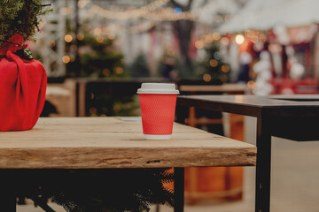 Red Takeaway Coffee Cup on Wooden Table in Cozy Outdoor Cafe