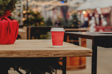 Red Takeaway Coffee Cup on Wooden Table in Cozy Outdoor Cafe