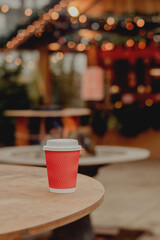 Red Takeaway Coffee Cup on Wooden Table in Cozy Outdoor Cafe