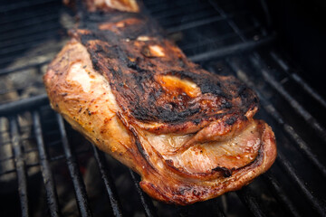 Meat is cooking on a hot grill with smoke rising in a backyard. It is summer and friends are gathered around enjoying the food and each other's company.