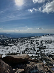 Snow-covered mountains under bright sun and clear sky panoramic view.
