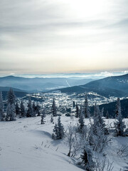 Mountain valley view with snowy forest and distant hills
