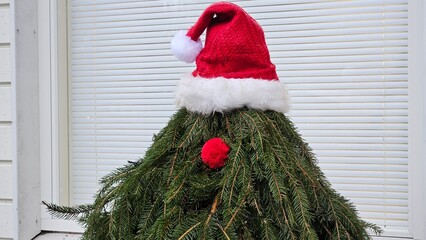 Minimalist Christmas Tree with Santa Hat and Red Nose Outdoors
