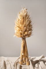 Didukh, traditional Ukrainian Christmas home interior decoration, handmade sheaf of wheat, holiday ritual attribute for Christmas Eve celebration, Didukh on linen cloth, neutral beige wall background